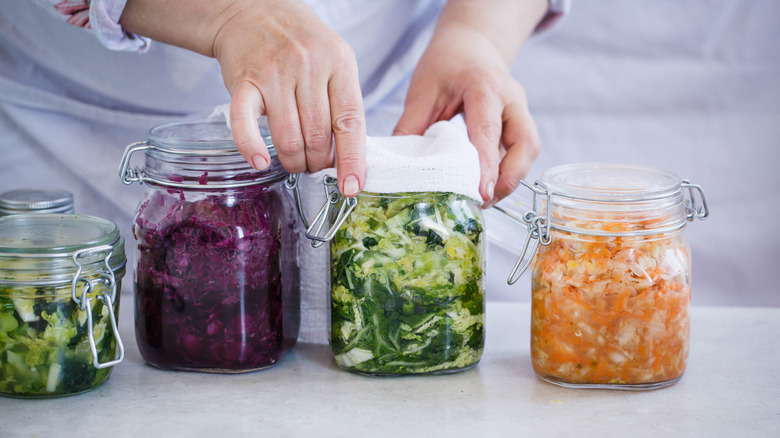 Woman storing fresh vegetables in glass jars 