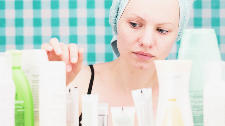 woman looking at many skincare products in bathroom