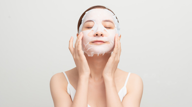 woman putting on sheet mask relaxed