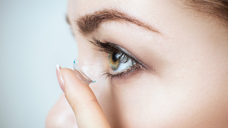 Extreme close up of a woman about to put a contact lens in her eye