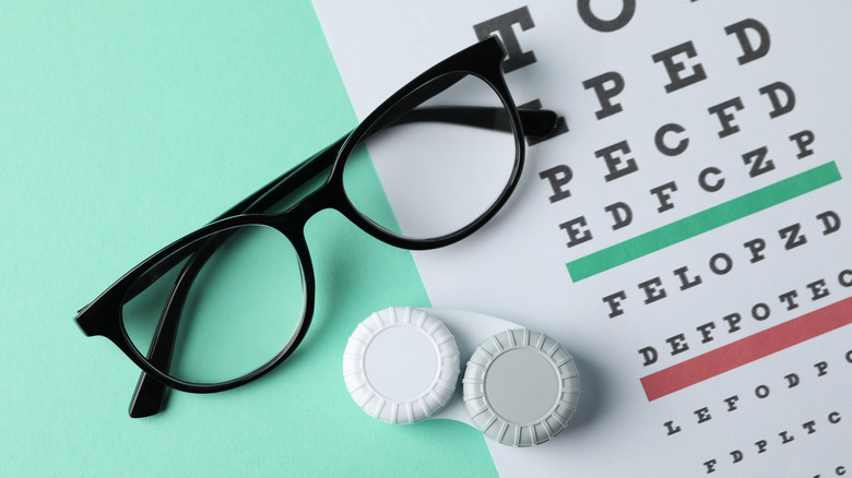A pair of glasses and contact lens case on top of an eye chart
