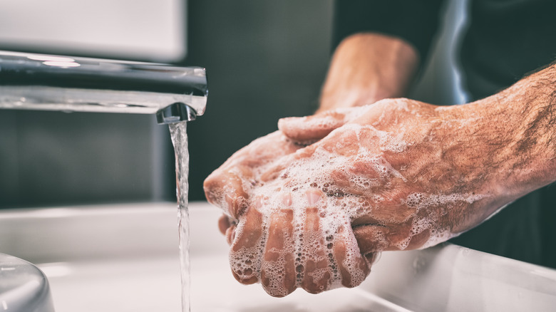 Close up of a person in a black shirt washing their hands with soap