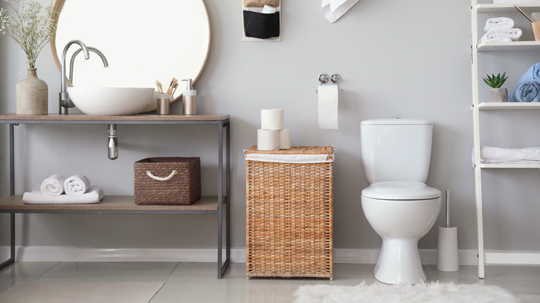 Bathroom with a round mirror above the sink and extra storage next to the toilet