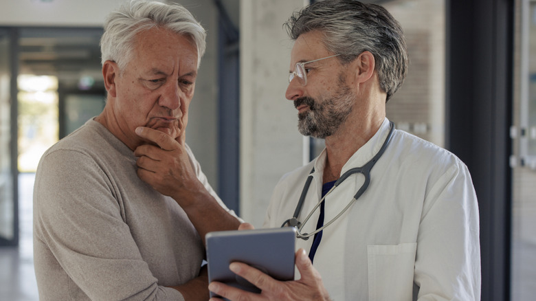 male doctor consulting with male patient in hallway