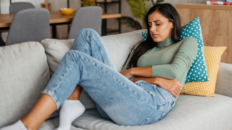 woman sitting on couch feeling constipated