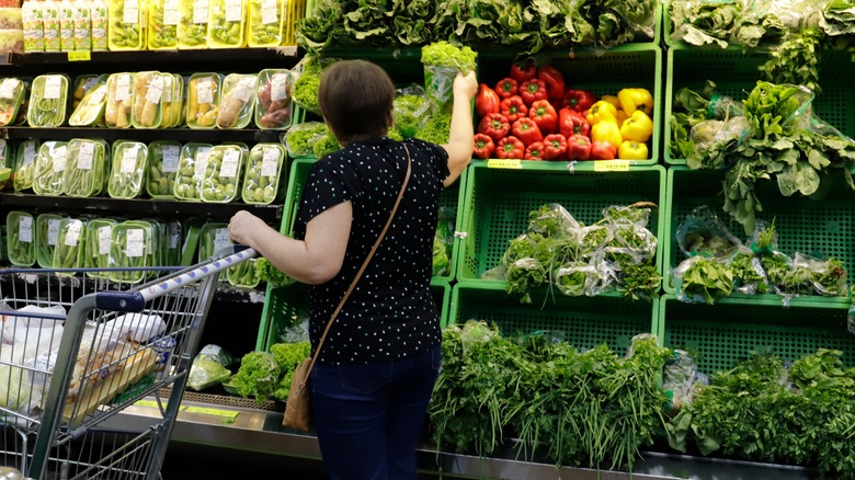 woman looking at leafy green vegetables in grocery