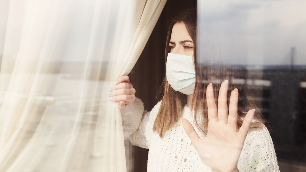 Young woman in medical mask stay isolation at home for self quarantine. 