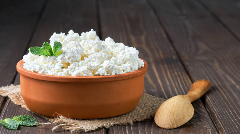 clay bowl of cottage cheese with wooden spoon