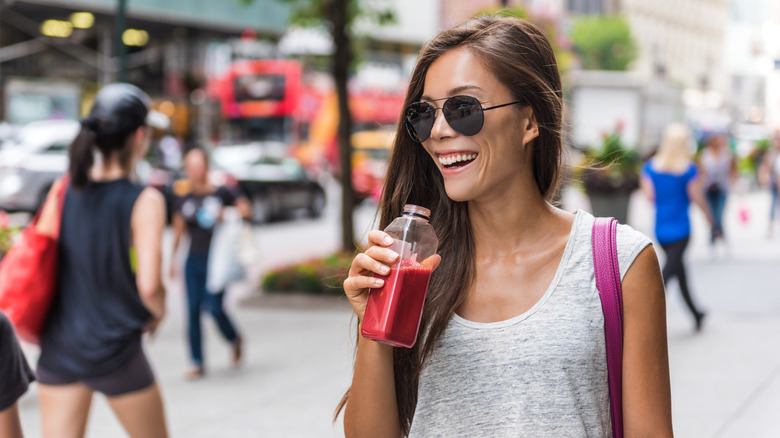 woman walking through the city drinking beet juice