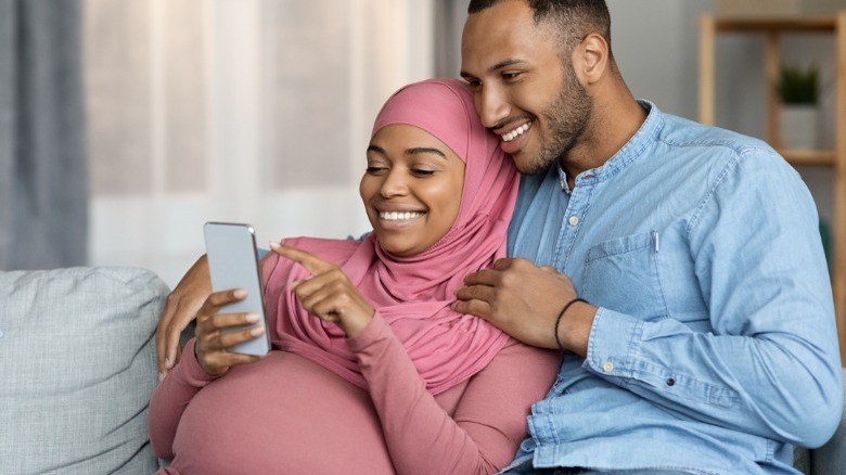 pregnant woman looks at phone with partner