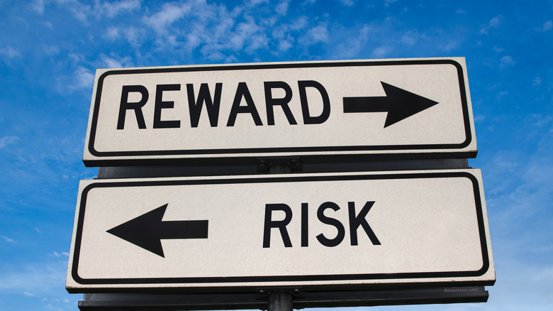 one street sign pointing to "REWARD" and the other pointing to "RISK"