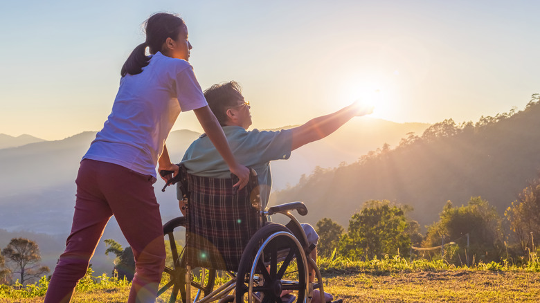 woman pushing man's wheelchair outside