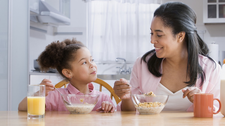 A woman and her daughter eating a bowl of cereal