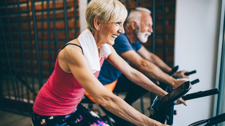 an older man and woman smiling through a cycling class