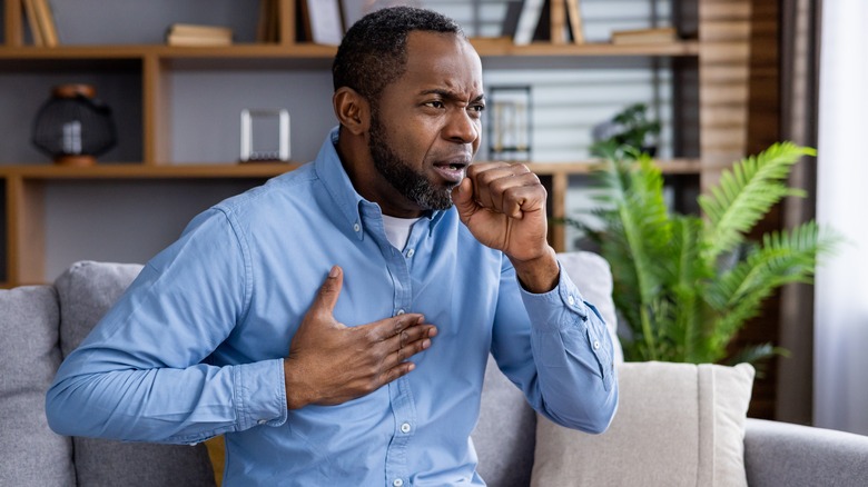 Coughing man holding chest