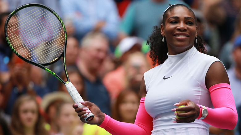 Serena Williams smiling and holding racket