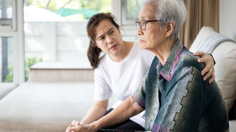 Someone comforts an elderly woman