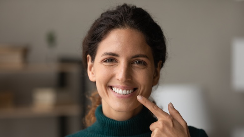  woman smiling pointing to teeth