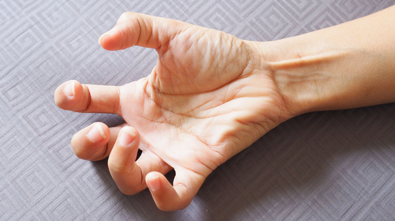 Hand with convulsions and muscle spasms against a gray background