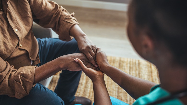 nurse holding older male patient's hands in gesture of comfort