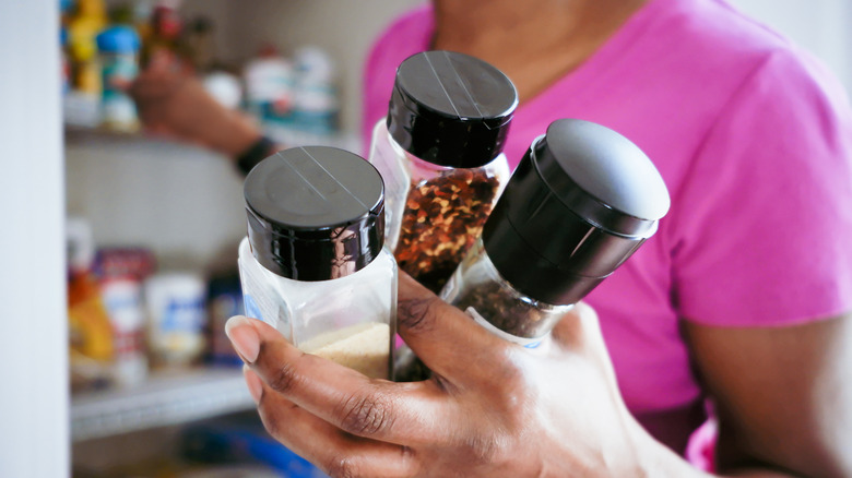 A woman's hand grabbing spices from the pantry