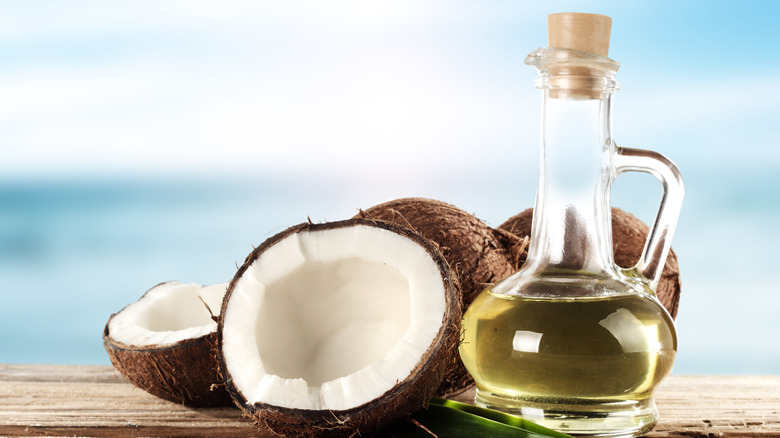 coconut and oil in a glass bottle on wooden platform