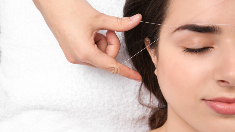 young woman having her eye brows professionally threaded