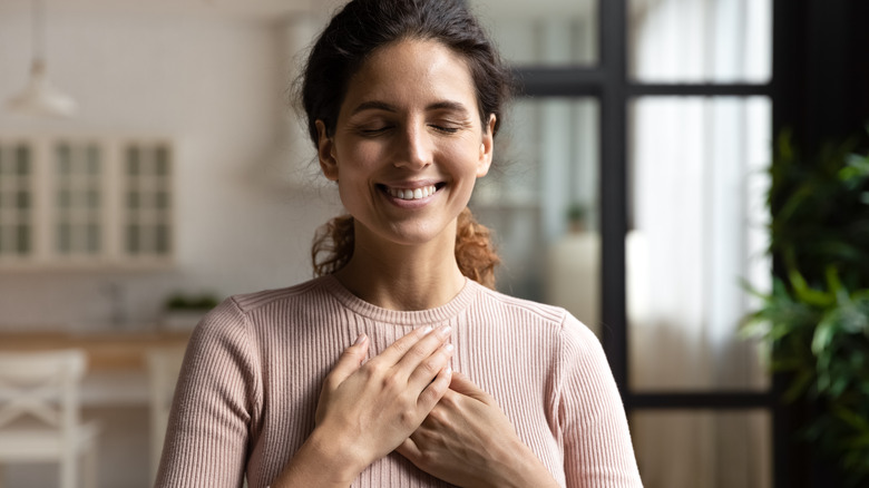 woman smiling with hands over heart