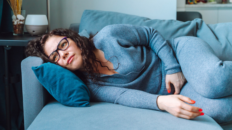 A woman lying on the couch feeling constipated