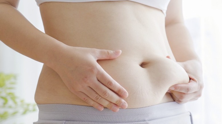 Woman grabbing abdominal fat