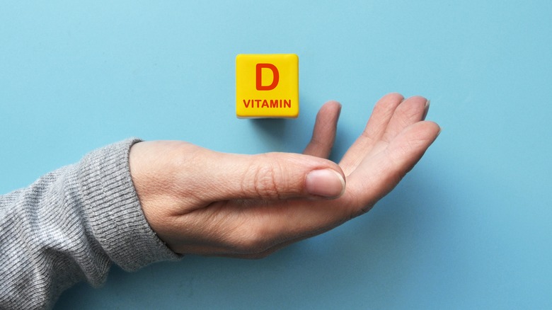 Vitamin D wooden block over a person's hand