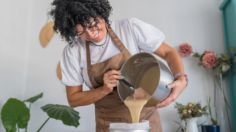 A woman pouring cake batter into a pan