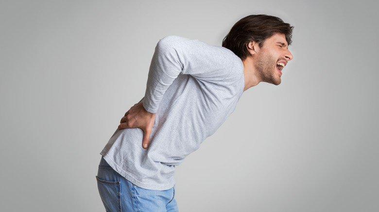 young man with kidney stones arching over in pain 