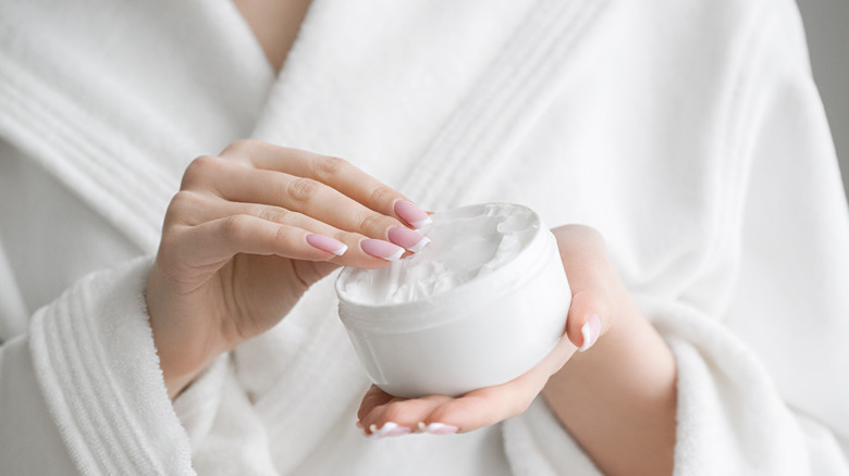 Woman dipping hands into lotion