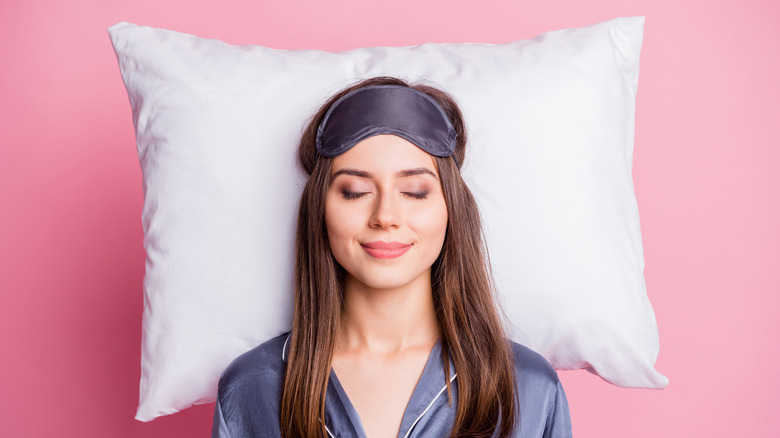 Top angle view photo of smiling woman sleeping on pillow isolated on a pink background