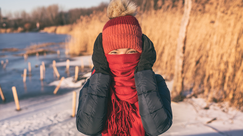 Woman bundled up covering ears 