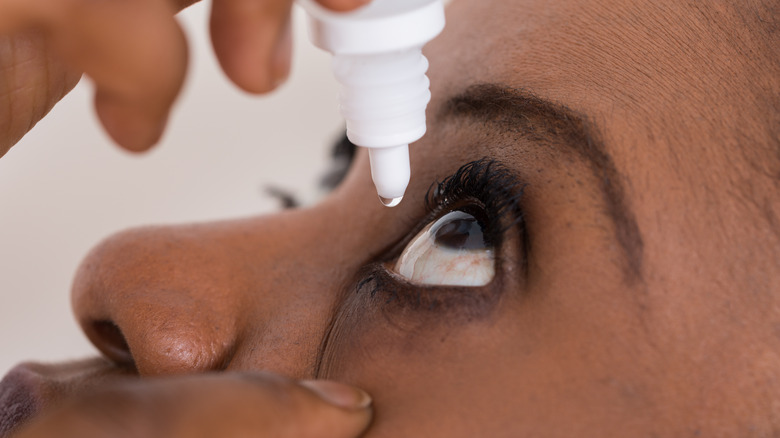 woman putting saline drops in eye