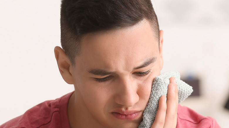 man using cold compress on face for toothache