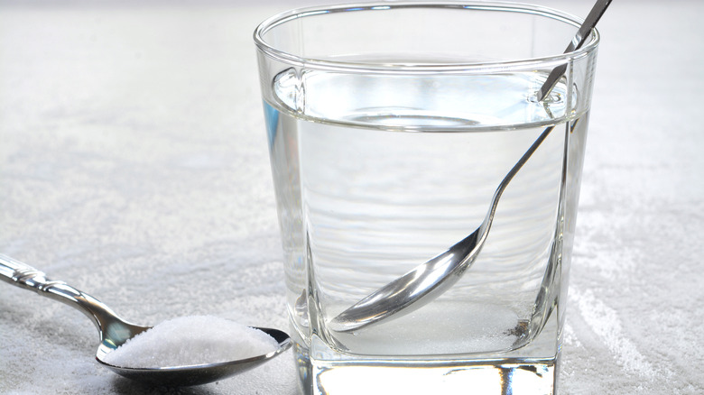 A glass of water next to a spoon full of salt