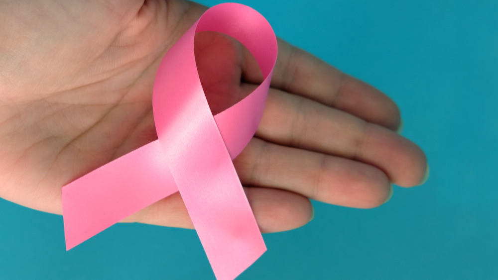 Hand holding a pink breast cancer ribbon