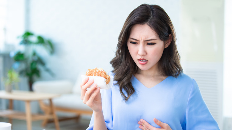 A woman is nauseous while eating a hamburger