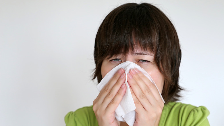 A woman pinching her nose in a napkin