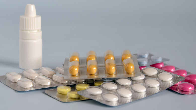 ﻿﻿Close up of tablets and pills in blister pack, medications, and white plastic medical container for nasal spray.