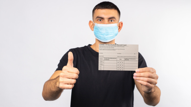 man holding COVID-19 vaccine card