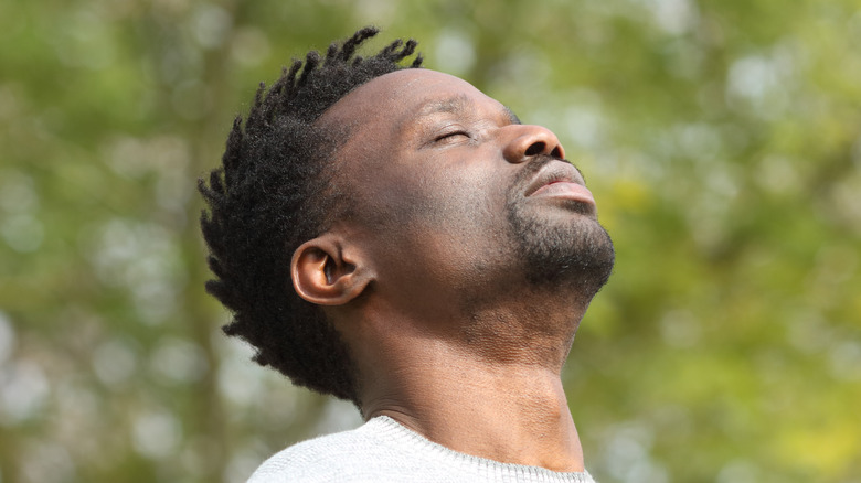 black man taking a deep breath outside