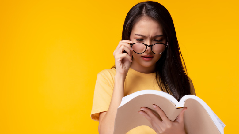 Woman wearing eyeglasses and holding text book 