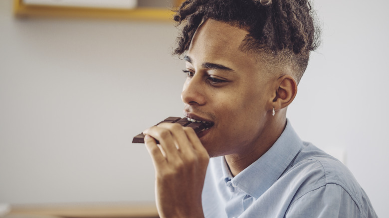 Young man eating chocolate bar