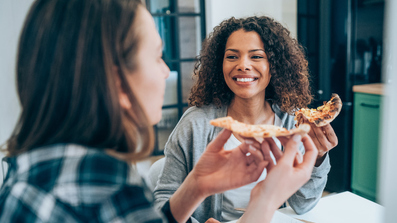 Smiling women eating pizza