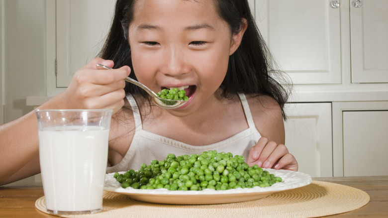young girl eating peas