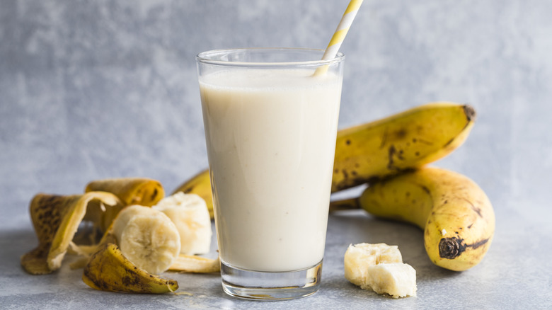 glass of banana milk surrounded with ripe bananas 